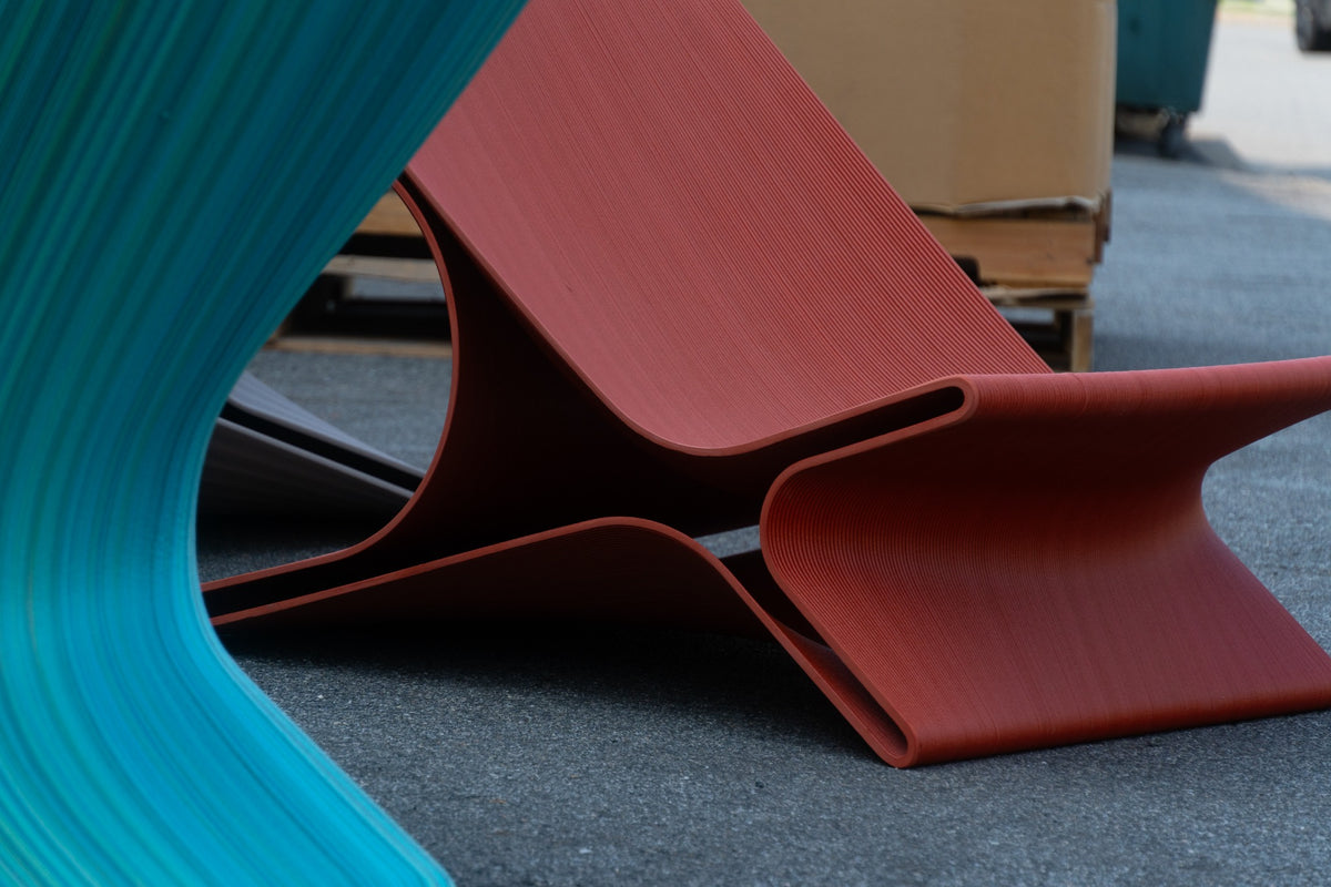 Close view of layered teal and rust 3D-printed chair surfaces and curved edges.