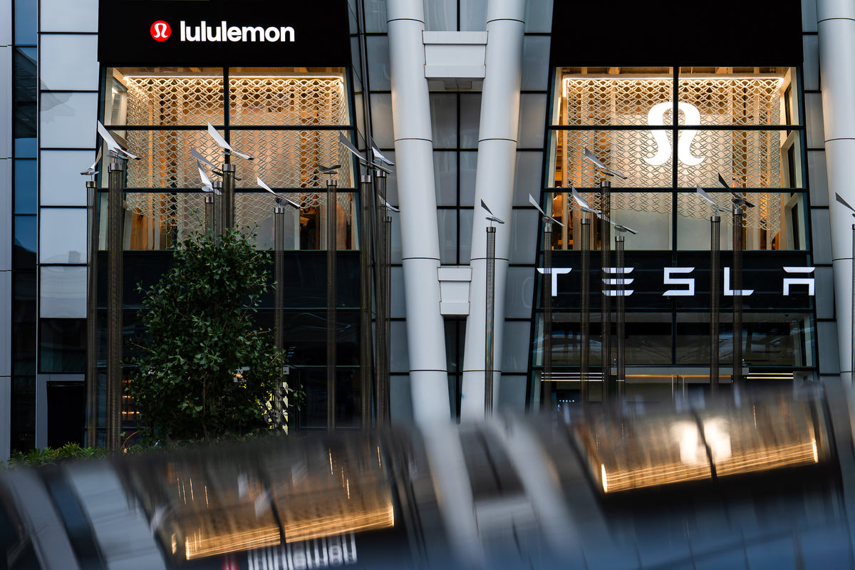 Wide view of two illuminated lululemon Prudential Center bays with the printed mesh installation reflected across a dark foreground surface.