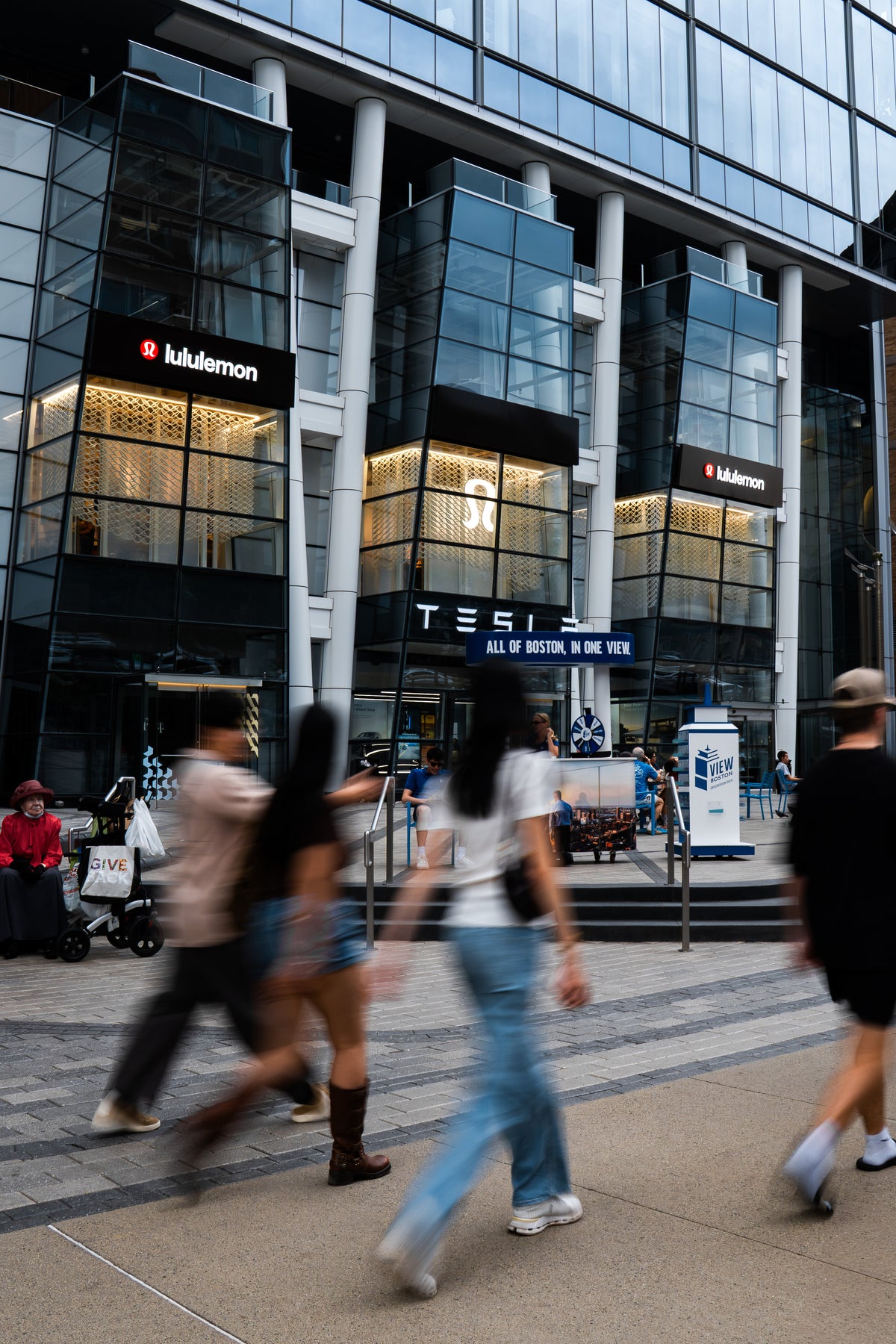 Daytime street view of lululemon’s three Prudential Center window bays with pedestrians moving through the foreground in Boston.