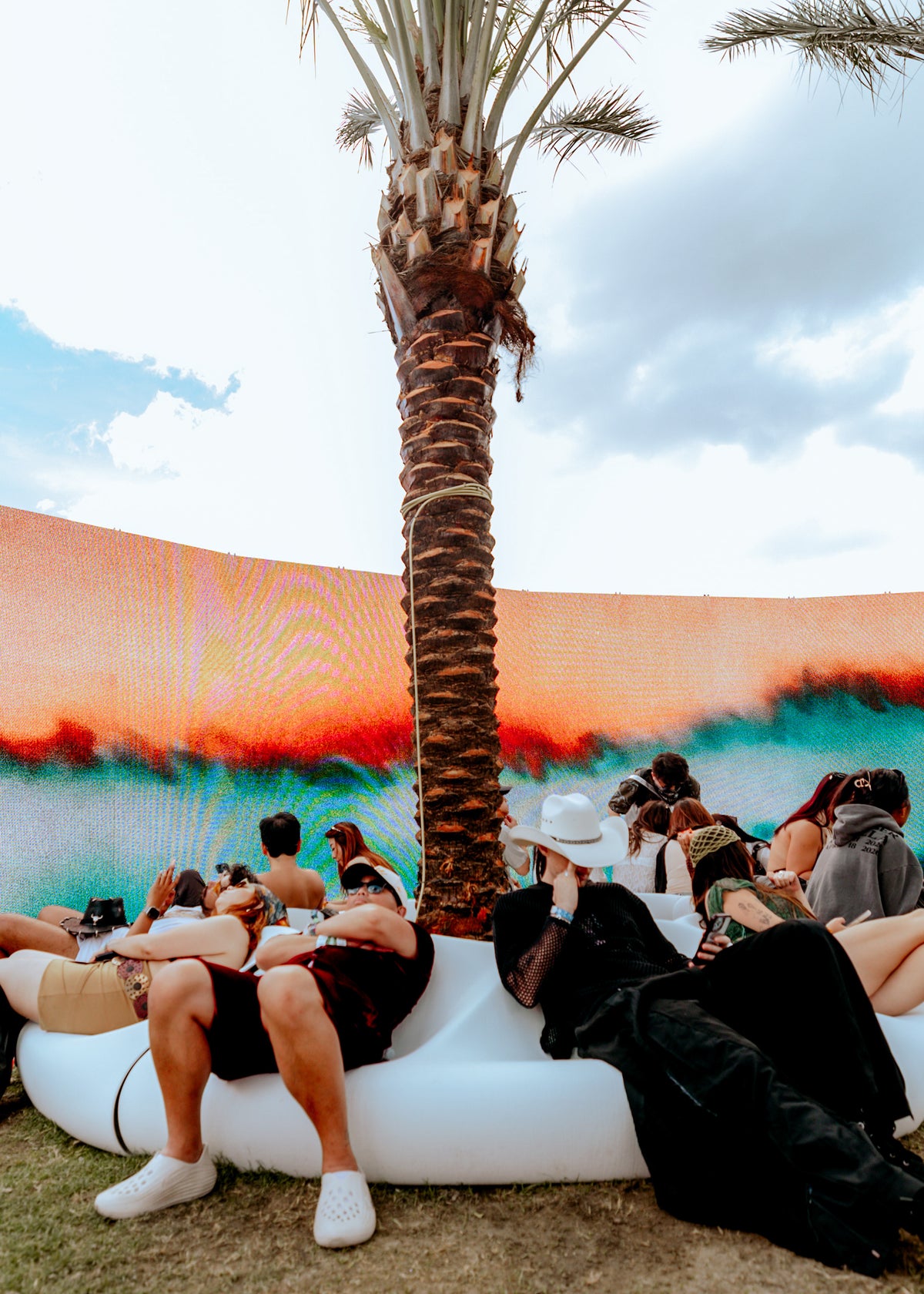 White modular seating around a palm tree against a colorful backdrop at SKYLRK’s Coachella installation.