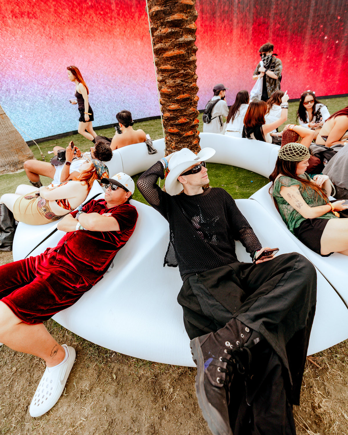 Visitors gathered on white sculptural Decibel benches beneath palm trees at SKYLRK’s OASIS at Coachella