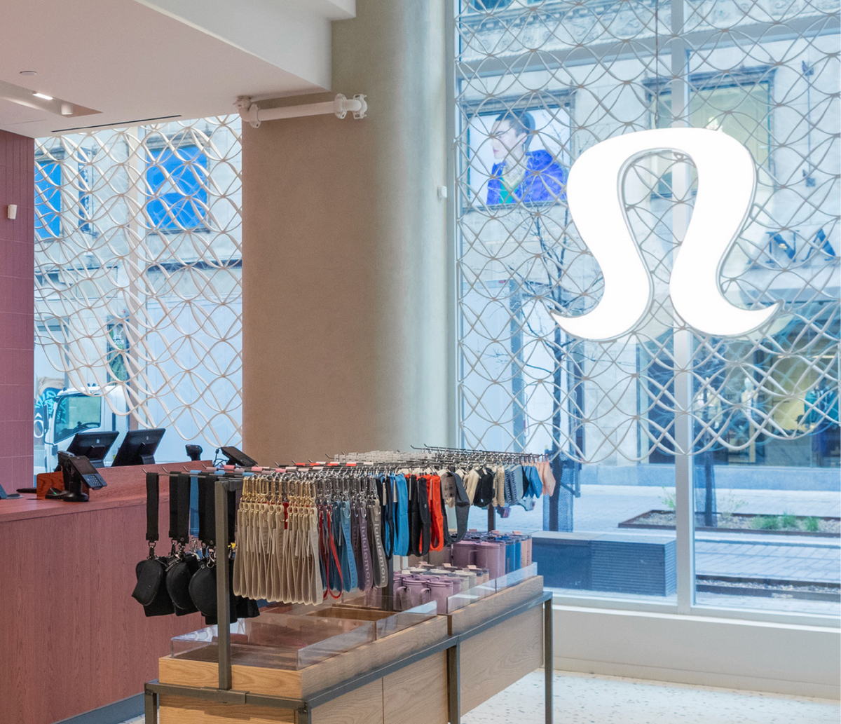 Interior view of lululemon’s Montréal store with architectural mesh behind the illuminated window logo.