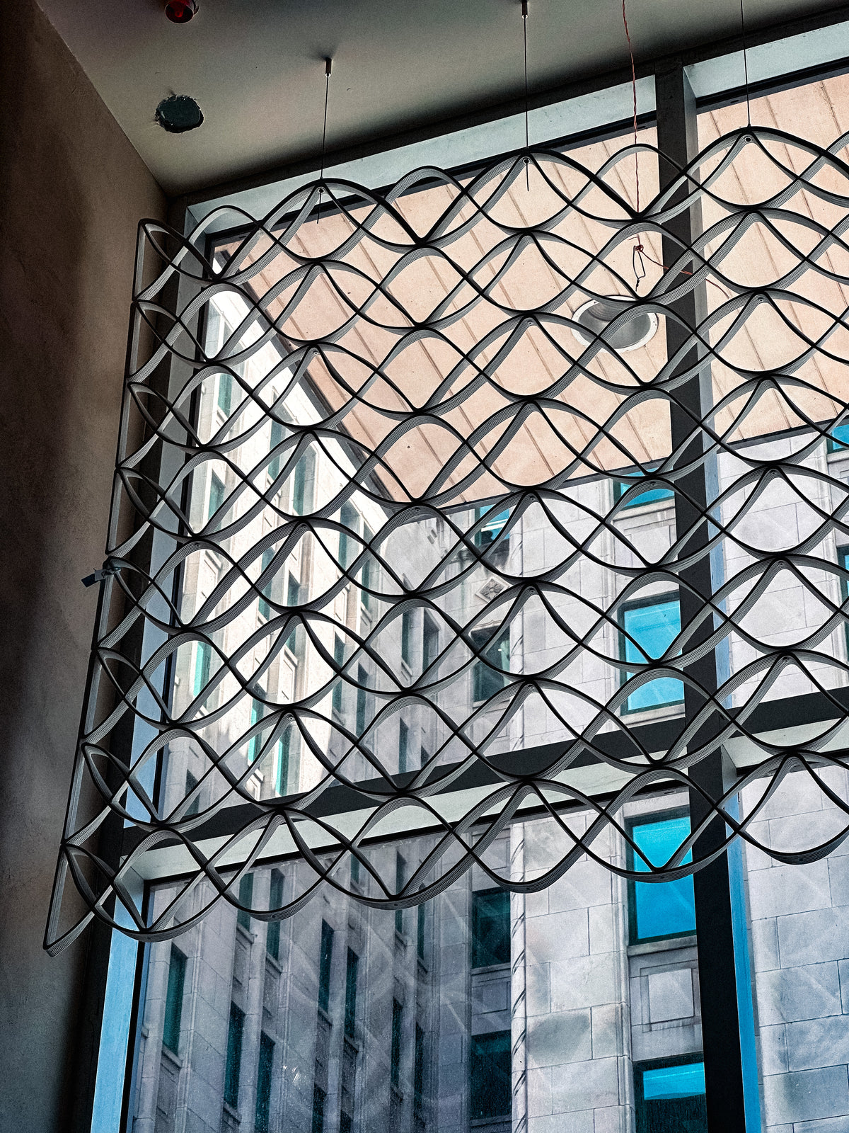 Architectural mesh suspended across a tall window inside lululemon’s Montréal flagship.