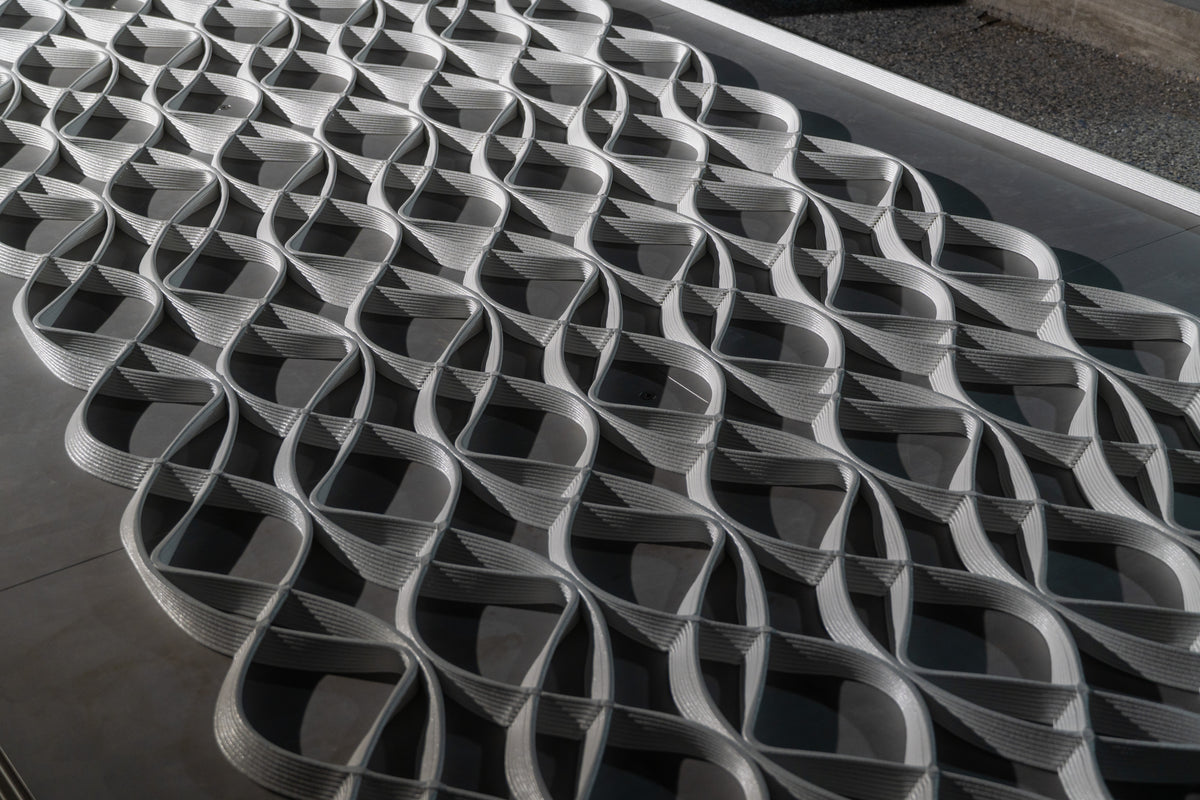 Close-up of the layered, looping geometry of a white architectural mesh panel.