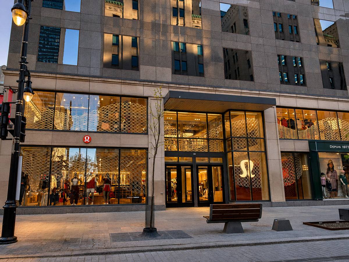 lululemon’s Montréal storefront at dusk, with illuminated architectural mesh behind the windows.