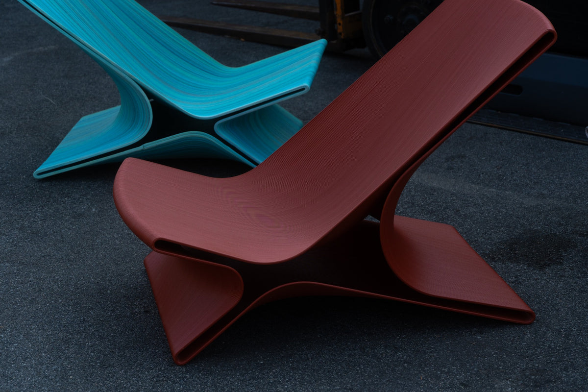 Teal and rust sculptural 3D-printed chairs displayed together in the Decibel workshop.