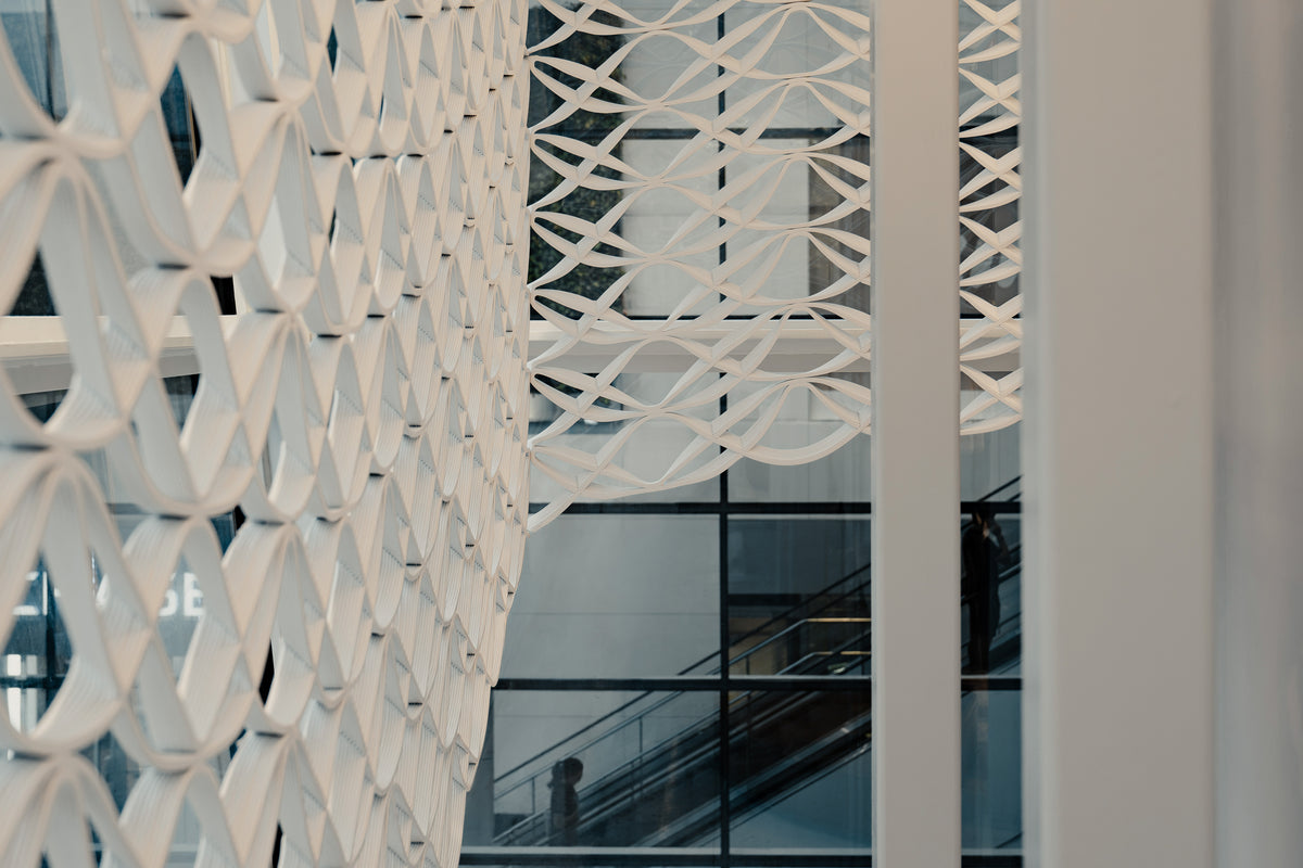 Close architectural view through layered white printed mesh at lululemon Prudential Center, showing the repeating geometry and depth between panels.