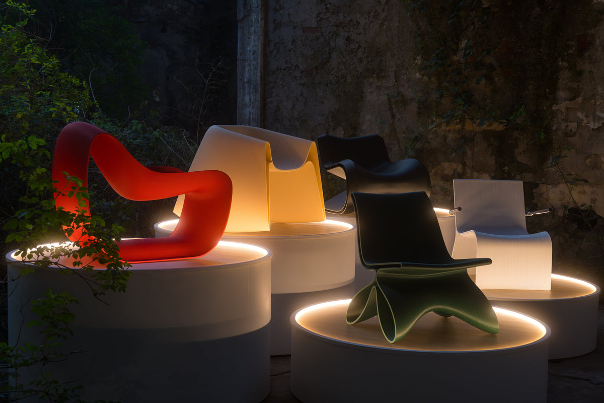 Colorful designer chairs displayed on illuminated circular plinths at the PORTAL exhibition.