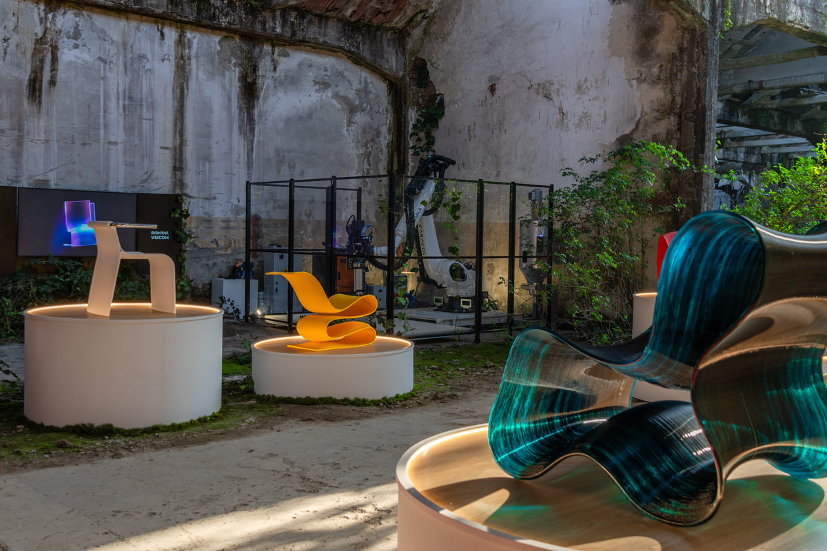 Teal, yellow, and natural-colored chairs on white plinths at the PORTAL exhibition.