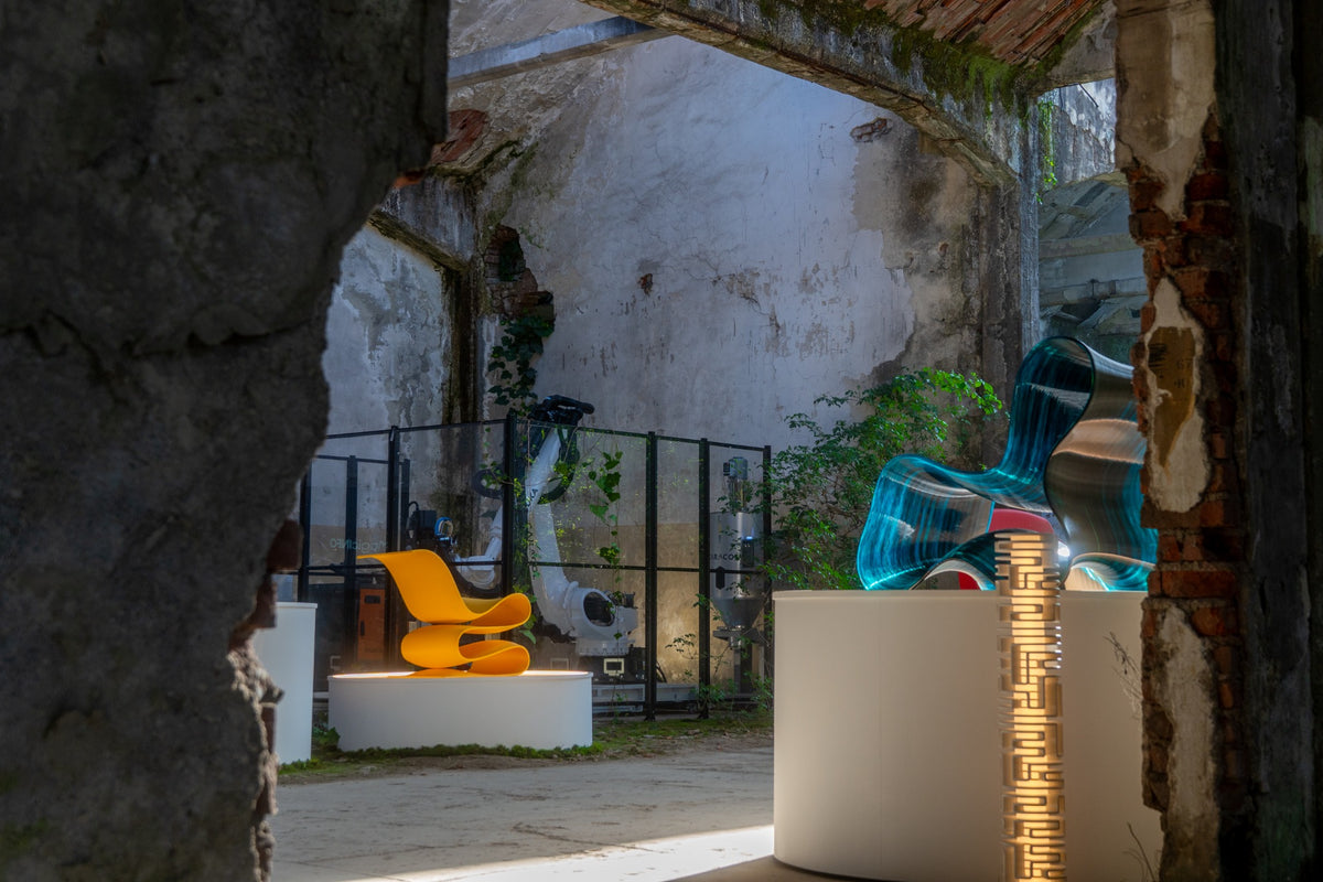 PORTAL at Alcova in Milan, viewed through the former SNIA factory ruins toward sculptural chairs and the live robotic fabrication cell.