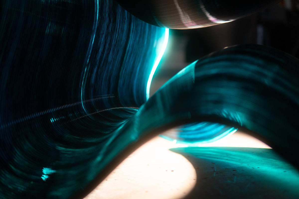 Close-up of the layered, translucent teal surface of a sculptural chair.