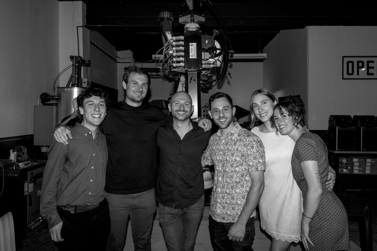 A group standing together in a robotic fabrication workshop.