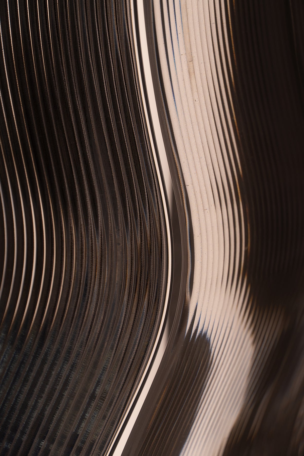 Close-up of curved translucent printed layers with warm light passing through the surface.