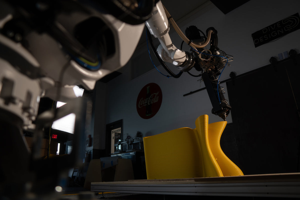 A robotic print head producing a yellow chair at Decibel