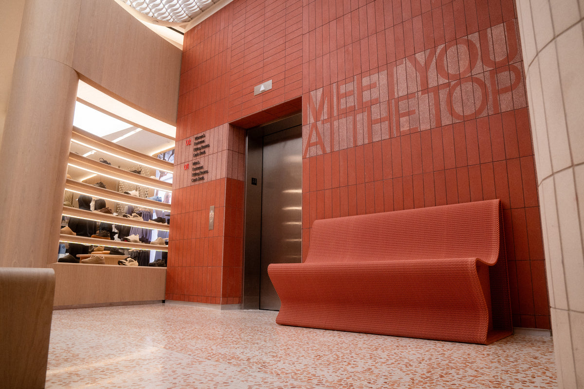 Custom red bench beneath fitting-room signage in lululemon’s SoHo store.