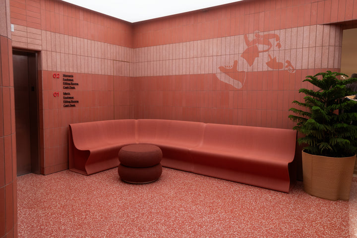 Red custom benches and round seating in the tiled interior of lululemon’s SoHo flagship.