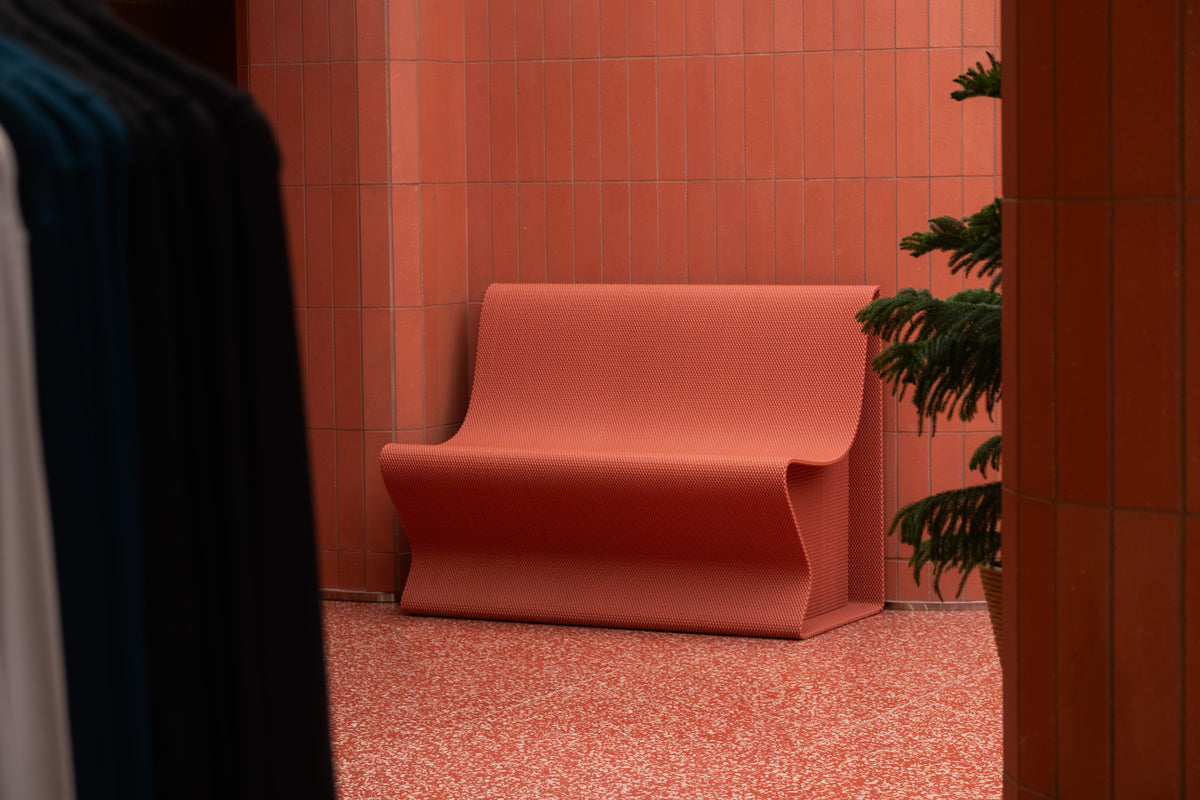 Custom red retail bench beside a planter at lululemon’s SoHo flagship.